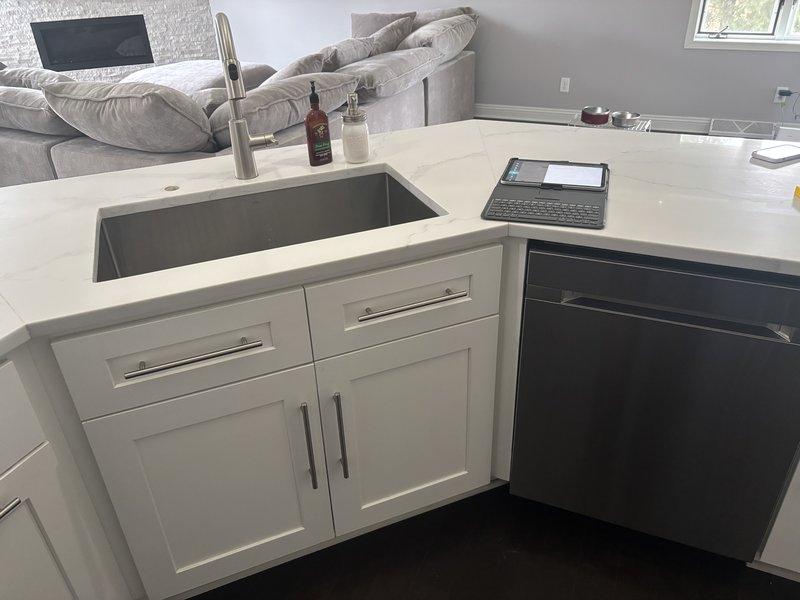 Performed inspection of kitchen sink installation and identified significant concrete deterioration measuring 26-30 inches in surrounding area. Documented surface damage showing extensive pitting and discoloration that may indicate water infiltration or material breakdown requiring remediation.