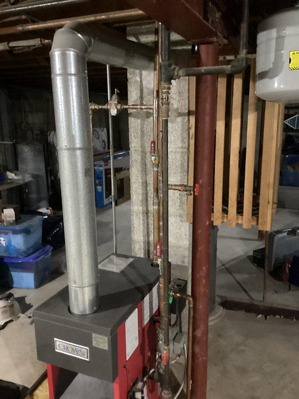 Performed comprehensive tune-up service on Crown boiler system located in basement utility area. Inspected all components including circulator pump, copper piping connections, and metal vent stack for proper installation and operation. Cleaned and tested system, confirming optimal performance with no issues detected in the heating equipment.