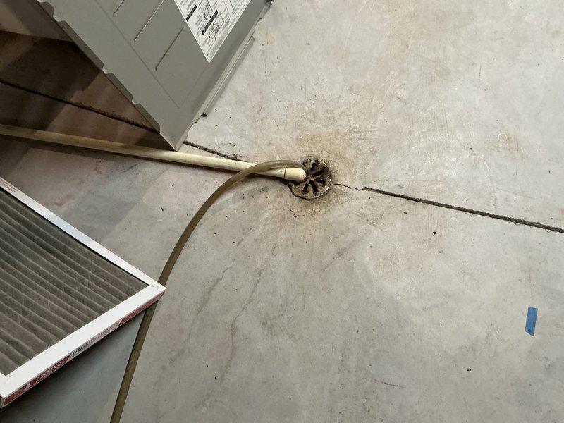 Performed comprehensive assessment of existing residential furnace system located in basement utility area. Documented current installation configuration including ductwork connections, PVC intake/exhaust venting, and electrical connectivity. Noted concrete floor condition showing cracks with drain access point and existing electrical conduit placement for replacement planning purposes.