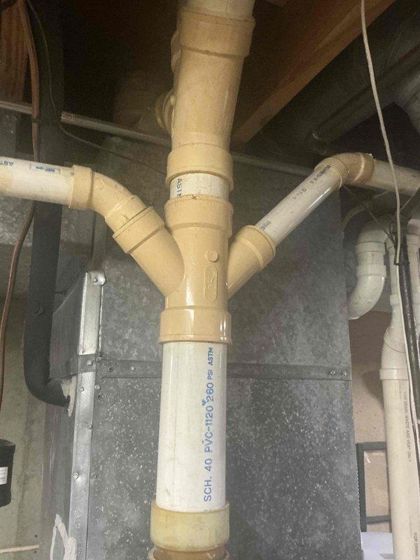 Completed inspection of existing condensate drain system for HVAC unit. Identified significant mineral buildup and discoloration on PVC piping, particularly at the Y-junction. Noted potential drainage issues with the current configuration. Recommended replacement of affected PVC sections, including the primary vertical pipe and associated fittings, with new Schedule 40 PVC to prevent future backups and water damage.