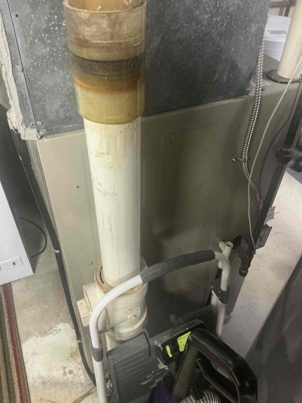 Completed inspection of existing condensate drain system for HVAC unit. Identified significant mineral buildup and discoloration on PVC piping, particularly at the Y-junction. Noted potential drainage issues with the current configuration. Recommended replacement of affected PVC sections, including the primary vertical pipe and associated fittings, with new Schedule 40 PVC to prevent future backups and water damage.