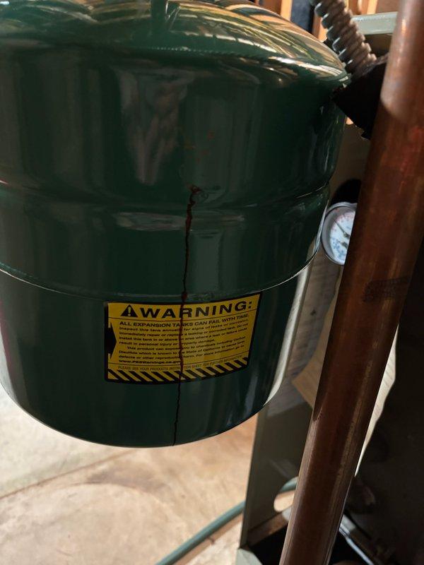 Performed visual inspection of expansion tank on boiler system, noting proper installation but identifying water staining on concrete floor beneath unit. Checked system pressure gauge which showed normal operating range. No immediate remediation was required, but recommended monitoring for possible slow leak at tank or nearby copper pipe connections.