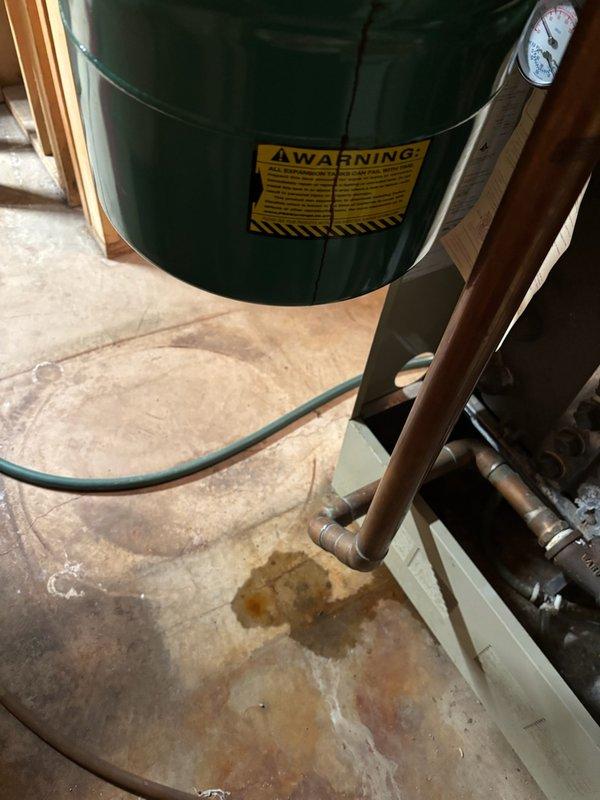 Performed visual inspection of expansion tank on boiler system, noting proper installation but identifying water staining on concrete floor beneath unit. Checked system pressure gauge which showed normal operating range. No immediate remediation was required, but recommended monitoring for possible slow leak at tank or nearby copper pipe connections.