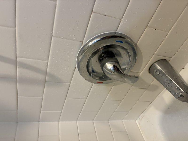 Successfully installed a chrome shower/tub combination fixture including a lever-handle temperature control and matching bathtub spout on white subway-tiled wall. Tested operation and confirmed proper water flow and temperature regulation with no leaks present at connection points.