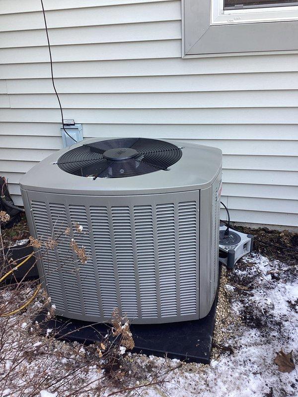 Successfully completed installation of a new residential HVAC system, including placement of the outdoor condenser unit on a level pad adjacent to the home's exterior. System installation included proper electrical connections with protective conduit and appropriate drainage setup through the concrete floor to ensure proper condensate removal.