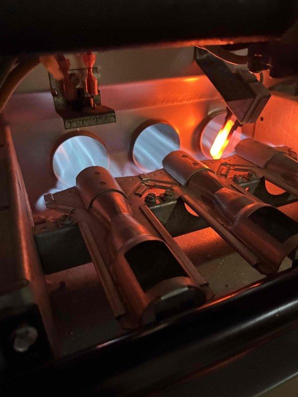 Performed combustion analysis on heating system using Testo 310 gas analyzer, documenting flue gas readings including stack temperature (293.2°F), oxygen (7.0%), CO (10 ppm), and efficiency (44.8%). Inspected burner assembly and verified proper flame characteristics with three blue flames visible through heat exchanger tubes, indicating normal operation after addressing the no heat complaint.