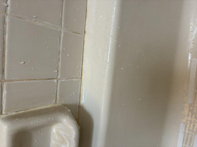 Completed installation of new shower/tub unit with proper sealing and caulking at all wall junctions. Applied waterproof sealant along fixture-to-wall seams to prevent water intrusion. Tested installation for proper drainage and water-tightness with all surfaces demonstrating appropriate water beading and no leakage at tile-to-fixture transitions.