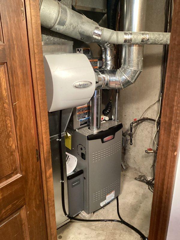 Successfully installed a complete residential HVAC system in the utility closet, featuring a new gray furnace unit with an Aprilaire humidifier attachment. Installation included proper mounting of the furnace on concrete flooring, comprehensive ductwork installation with both metal and insulated sections secured with metallic tape, and complete electrical connections to ensure optimal system functionality.