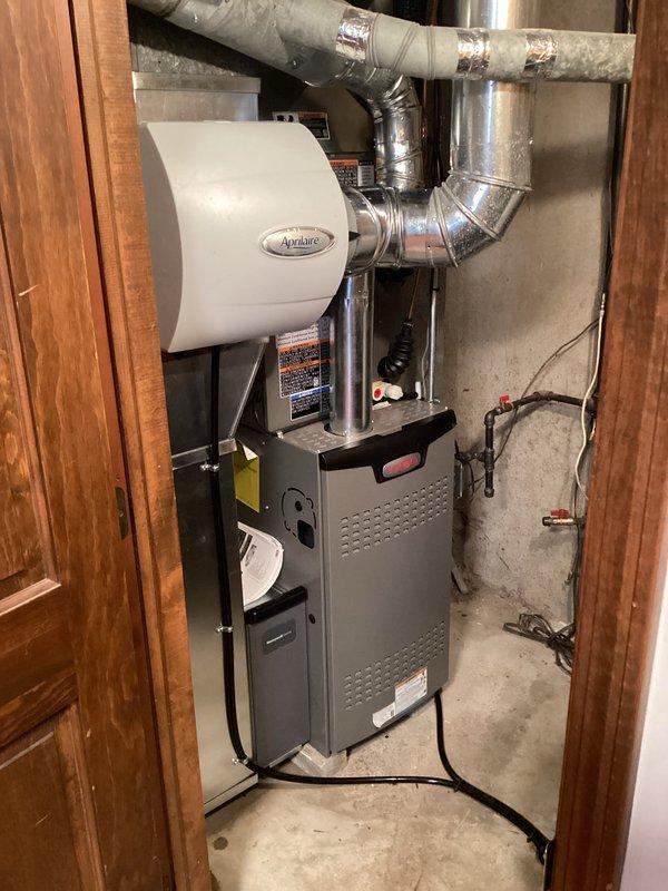 Successfully installed a complete residential HVAC system in the utility closet, featuring a new gray furnace unit with an Aprilaire humidifier attachment. Installation included proper mounting of the furnace on concrete flooring, comprehensive ductwork installation with both metal and insulated sections secured with metallic tape, and complete electrical connections to ensure optimal system functionality.