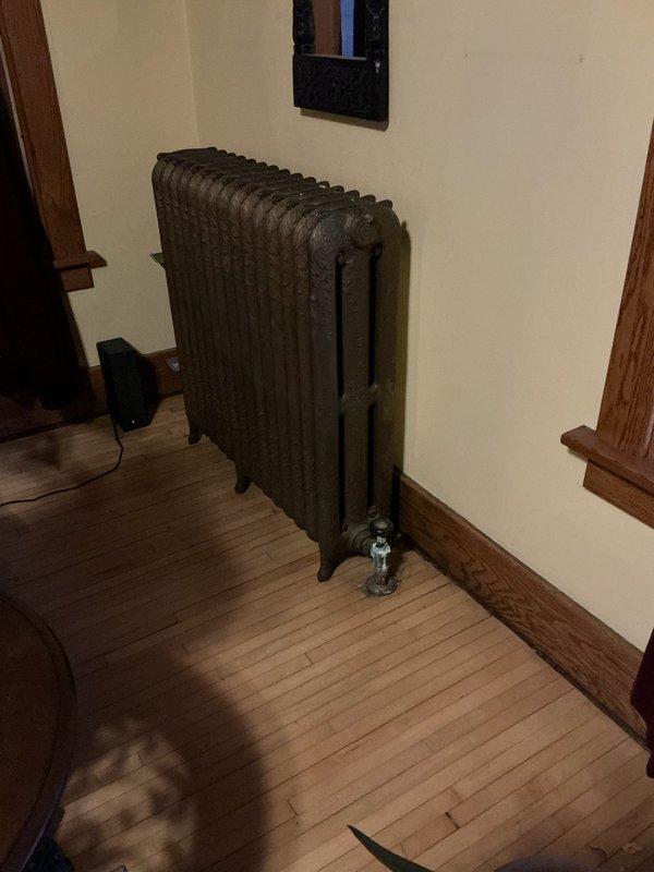 Performed routine maintenance inspection on antique cast iron radiator system. Identified significant corrosion and mineral buildup on water valve/shut-off fixture, with visible copper oxidation and evidence of previous water leakage. Recommended replacement of deteriorated valve assembly to prevent potential failure and water damage.