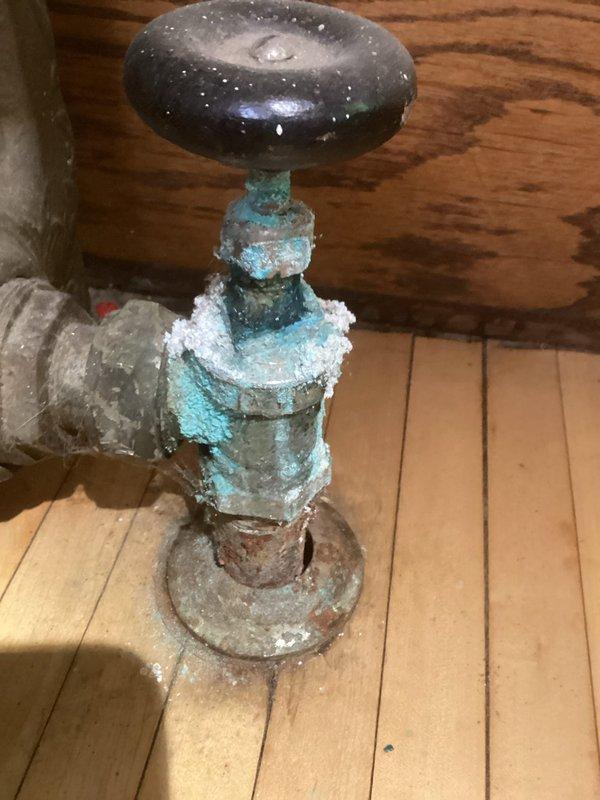Performed routine maintenance inspection on antique cast iron radiator system. Identified significant corrosion and mineral buildup on water valve/shut-off fixture, with visible copper oxidation and evidence of previous water leakage. Recommended replacement of deteriorated valve assembly to prevent potential failure and water damage.