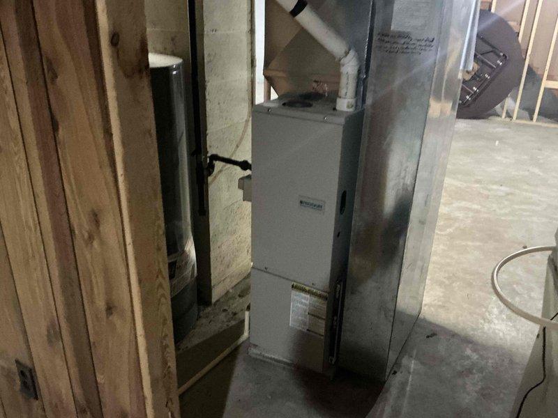 Conducted inspection and provided estimate for replacement of outdated HVAC system in unfinished basement area. Current installation shows galvanized ductwork with white PVC venting pipes connected to existing air handler. Proposed replacement includes new furnace unit to be installed between wooden framing studs with proper connections to existing ductwork and venting system.