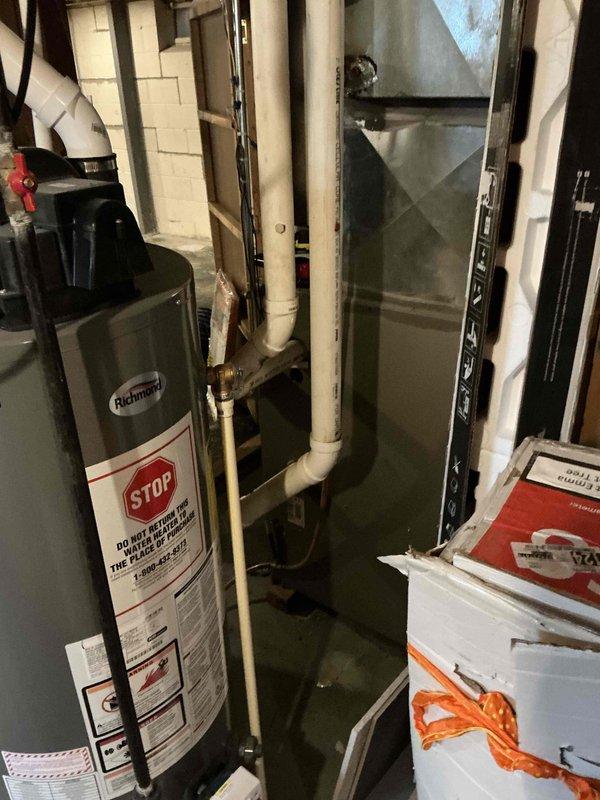 Completed inspection of existing HVAC system and water heater installation in utility room. Observed Richmond water heater with proper PVC venting (SCH 40 series) and evaluated current furnace system with access panel open for component assessment. Documentation photos taken of plumbing connections and mechanical equipment for replacement estimate preparation.