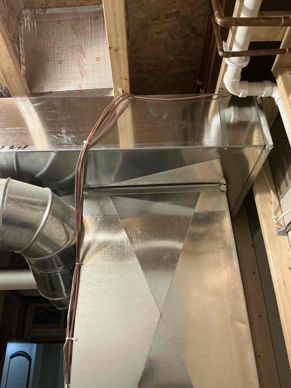 Conducted comprehensive inspection of existing HVAC system in basement utility area, focusing on ductwork configuration and air handler unit. Documentation included photographic assessment of the main metal air handler with connected round and rectangular ducts, noting overall good condition of metallic surfaces and proper installation of associated copper lines and control components. System appears well-maintained with no visible damage or deterioration requiring immediate attention.