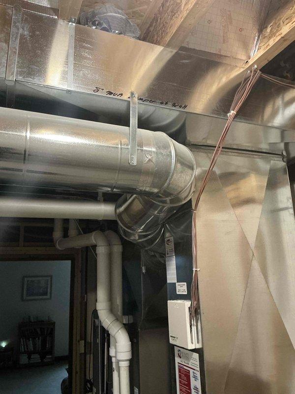 Conducted comprehensive inspection of existing HVAC system in basement utility area, focusing on ductwork configuration and air handler unit. Documentation included photographic assessment of the main metal air handler with connected round and rectangular ducts, noting overall good condition of metallic surfaces and proper installation of associated copper lines and control components. System appears well-maintained with no visible damage or deterioration requiring immediate attention.