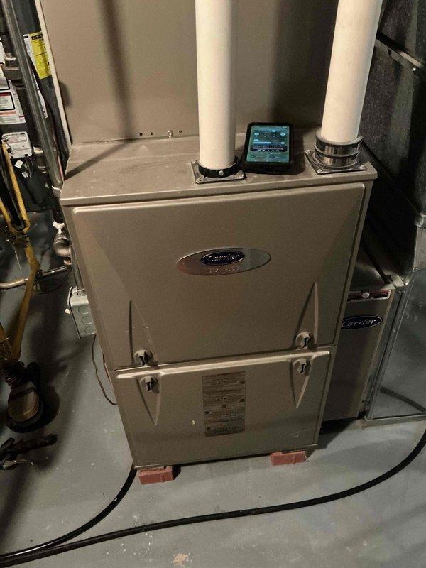 Performed routine maintenance on Carrier HVAC system, including inspection of ductwork which showed moderate dust accumulation and minor discoloration at junction points. Examined main furnace unit, checked PVC exhaust/intake pipes for proper ventilation, and verified operation of digital monitoring device. All components functioning within normal parameters.