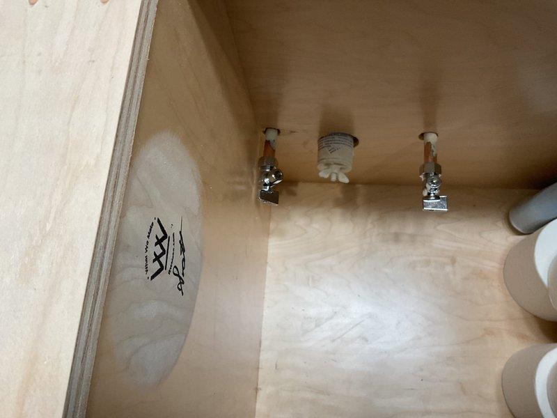 Conducted inspection of under-sink cabinet plumbing infrastructure, examining shut-off valves and supply lines. Identified potential installation points for new fixture. Documentation captured existing toilet paper storage configuration and current valve placement to ensure proper planning for upcoming fixture installation.