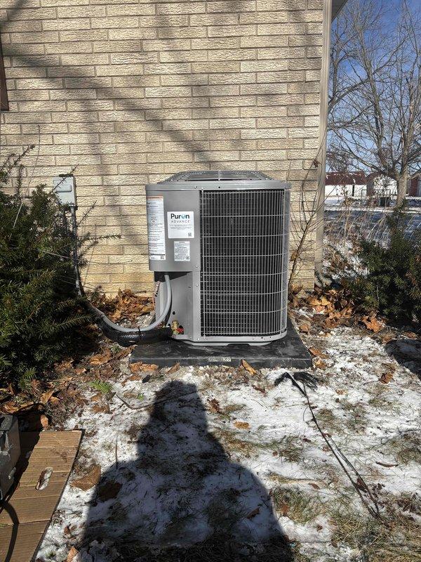 Successfully installed complete HVAC system including outdoor heat pump/AC unit mounted on concrete pad with proper refrigerant line connections. System includes modern digital programmable thermostat set to 63°F, with all components tested and functioning correctly.