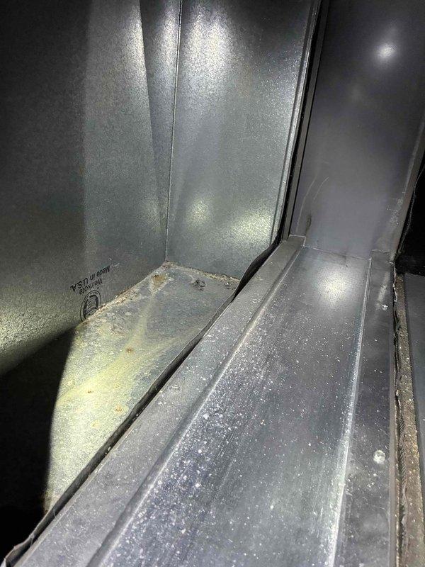 Performed inspection of metal ductwork system, examining interior surfaces for signs of corrosion and structural integrity. Observed minor discoloration and light corrosion along bottom seams of galvanized sheet metal, with some dust accumulation. System appears functionally intact with no significant damage requiring immediate repair.