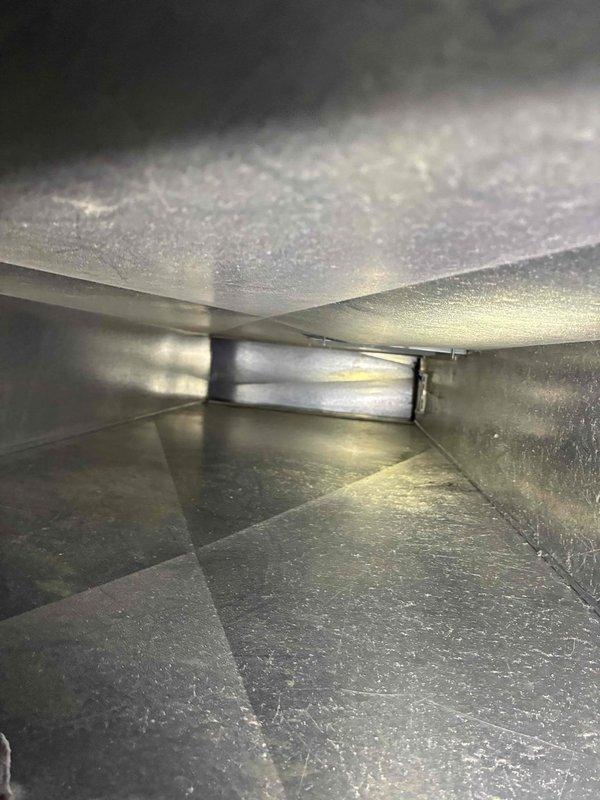 Performed inspection of metal ductwork system, examining interior surfaces for signs of corrosion and structural integrity. Observed minor discoloration and light corrosion along bottom seams of galvanized sheet metal, with some dust accumulation. System appears functionally intact with no significant damage requiring immediate repair.
