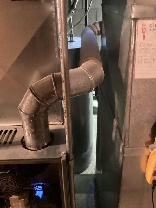 Performed comprehensive tune-up service on Rheem Criterion II gas furnace. Inspected internal components including blower motor, control board, and wiring connections. Examined exhaust venting system with particular attention to the 90-degree elbow joint, noting typical dust accumulation but confirming proper installation and function. Verified system operation with all safety mechanisms responding correctly as indicated by operational blue indicator light.