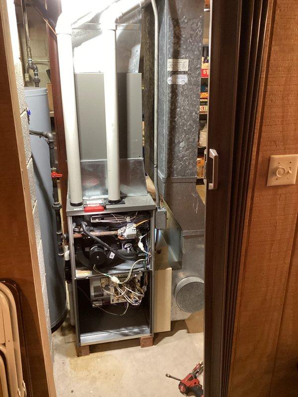 Performed routine tune-up on residential HVAC system located in basement utility area. Inspected furnace unit with front panel removed to examine internal components including wiring, motors, and control boards; all systems functioning properly. Verified proper operation of condensate drainage system and confirmed no leaks or damage to connected ductwork and piping.