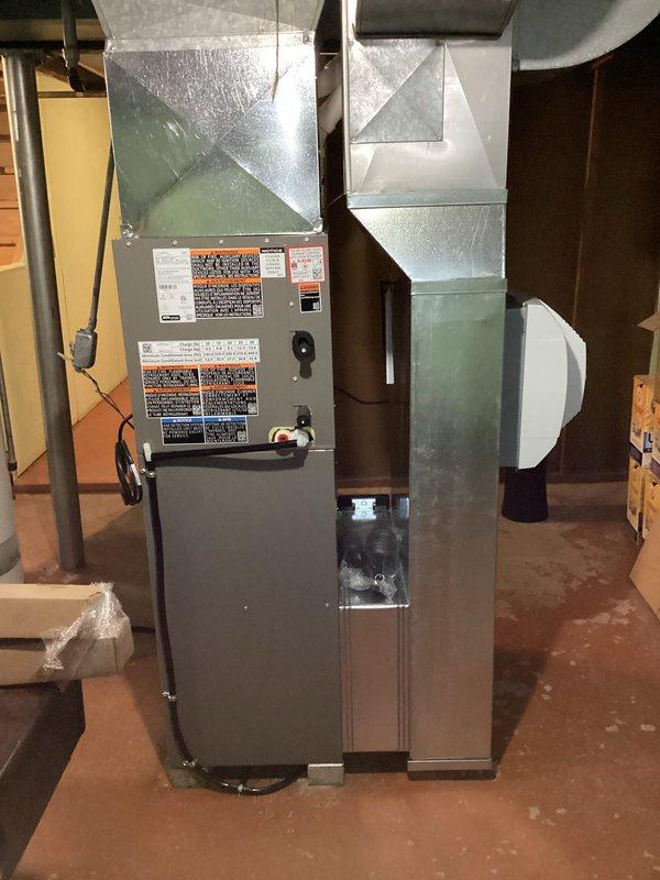 Completed installation of new HVAC system with high-efficiency furnace in basement utility area. System includes properly sealed metallic ductwork with multiple distribution branches. Noted existing floor drain shows significant corrosion; recommended monitoring for proper drainage to prevent potential water damage to new equipment.