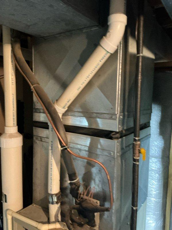 Completed inspection of existing HVAC system installation in utility space. Documented primary furnace/air handler unit with associated PVC exhaust/intake piping, copper refrigerant lines, and connected ductwork. System appears to have standard installation with proper venting configuration. Photos taken of plumbing connections and main HVAC unit for reference in replacement estimate.