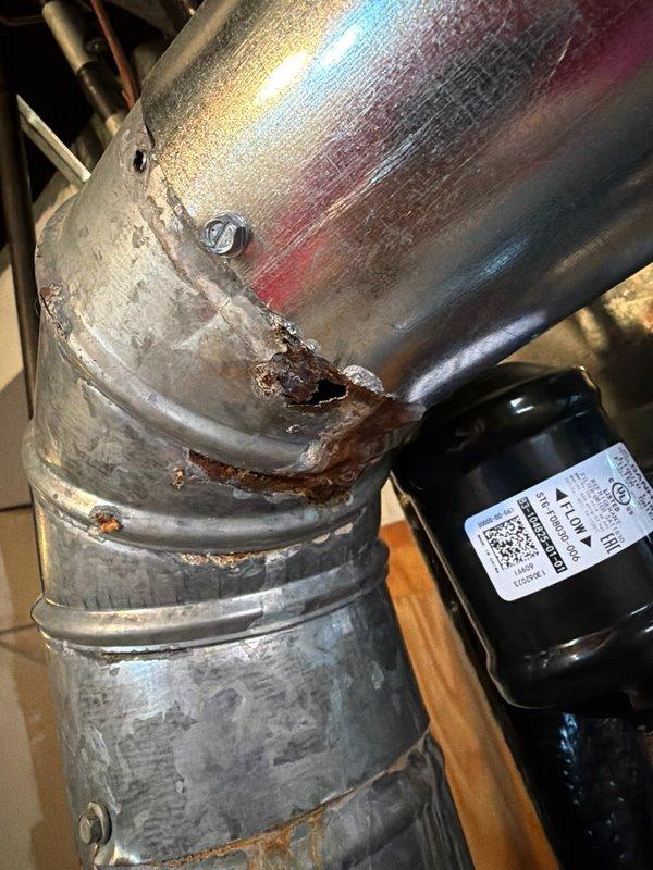 Inspected furnace system and discovered severe corrosion damage in the ductwork, particularly at connection points and a 90-degree elbow joint where complete metal failure has occurred. Documented extensive rust deterioration with multiple perforations that are compromising system integrity and efficiency. Recommended immediate replacement of affected ductwork sections to prevent further deterioration and potential safety hazards.