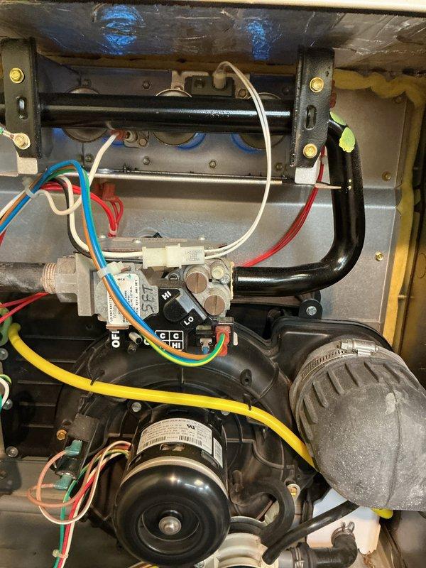 Conducted comprehensive tune-up on HVAC system with focus on motor assembly inspection. Examined electrical connections, verifying proper wire terminations and secure fastening of colored wires (blue, red, white, yellow, green) to control module and gas valve. Inspected blower motor for proper operation and mounting integrity. Checked gas valve functionality and verified control module operation with attention to switch positions. All components were found to be in serviceable condition with no signs of deterioration or damage.