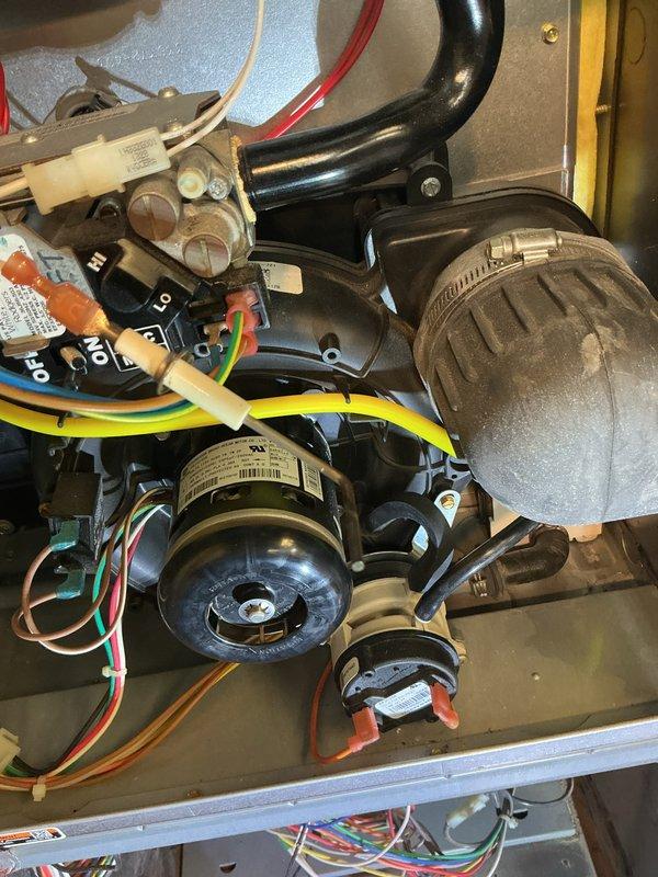 Conducted comprehensive tune-up on HVAC system with focus on motor assembly inspection. Examined electrical connections, verifying proper wire terminations and secure fastening of colored wires (blue, red, white, yellow, green) to control module and gas valve. Inspected blower motor for proper operation and mounting integrity. Checked gas valve functionality and verified control module operation with attention to switch positions. All components were found to be in serviceable condition with no signs of deterioration or damage.