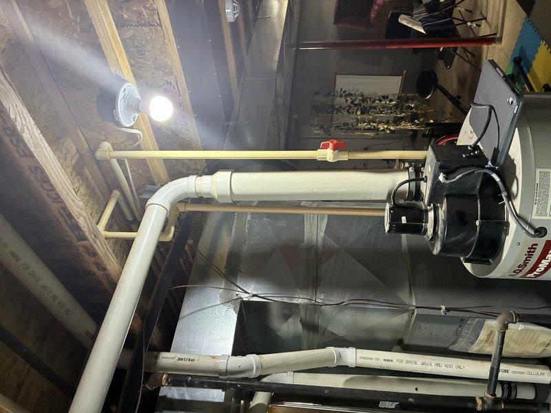 Conducted inspection of existing water heater installation in mechanical room. Evaluated PVC venting system, supply piping, and valve assembly. Documented current plumbing configuration including horizontal PVC pipe with metal bracket supports and functioning valve assembly connected to flexible supply line. Photos taken of complete system to reference for estimate preparation.