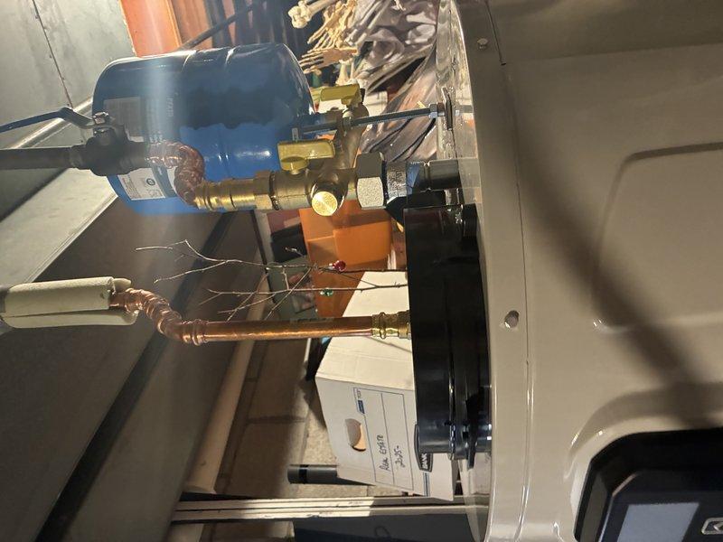 Completed installation of a tanked water heater system with associated PVC drainage piping and copper supply lines. Installed pressure regulator with float valve on the cold water inlet and properly connected all necessary brass fittings and valves for optimal system operation.