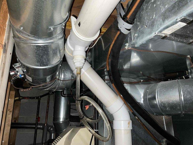 Completed inspection of existing HVAC ductwork system in utility/mechanical room. Identified aging galvanized metal ducts with multiple elbow joints, connected PVC drainage piping, and associated copper lines. System appears functional but shows signs of normal wear. Photographed current installation for reference in preparation for proposed replacement.