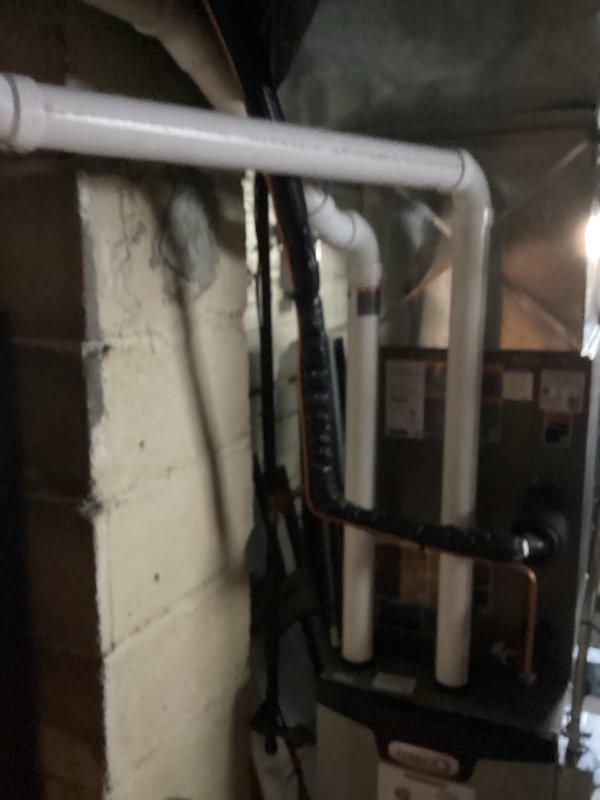 Conducted inspection of basement utility area to assess plumbing infrastructure connecting to HVAC system. Identified aging pipe joints with visible corrosion and mineral deposits at connection points between different pipe materials. Documented condition of support brackets and mounting hardware on ceiling installation for future reference.