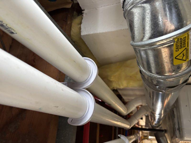 Inspected residential plumbing system and evaluated water heater installation requirements. Observed existing PEX piping configuration with proper metal clamp supports and examined ventilation ducting with appropriate clearance. Noted yellow insulation material in surrounding cavity spaces. System appears well-organized with standard connections and fittings for residential water heater installation.