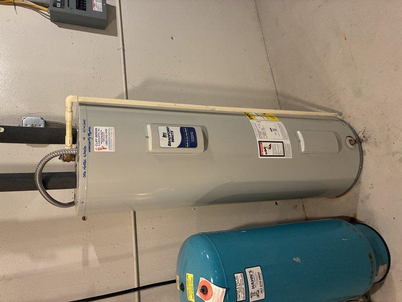Performed inspection of residential tanked water heater system located in utility room. Examined electrical connections at terminal block by accessing service panel. Verified proper installation of expansion tank and copper supply lines. System appeared to be in good working condition with no visible leaks or deterioration.