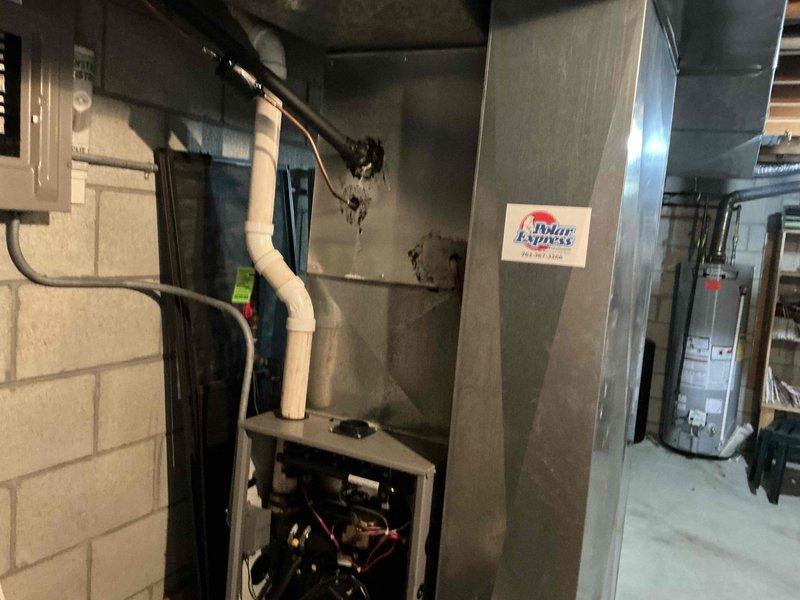 Conducted inspection of existing Polar Express HVAC system in basement mechanical room. Documented condensate drainage setup with PVC piping and identified access panel components. Photographed system connections and surrounding infrastructure for replacement estimate purposes.