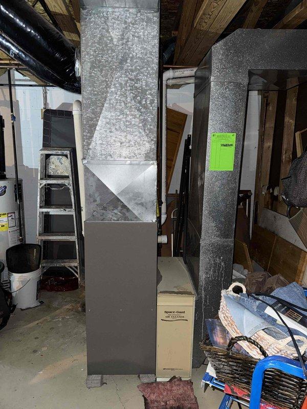 Conducted inspection of existing HVAC system in basement area. Assessed condition of current furnace/air handler unit with connected galvanized ductwork. Evaluated existing PVC venting system running through floor joists and Space-Gard air cleaner. Provided estimate for complete system replacement based on observed installation requirements and spatial constraints.