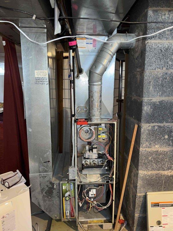 Performed comprehensive HVAC system replacement, installing new Carrier equipment including indoor furnace unit with updated control board and motor assembly. Completed installation of properly sealed metal ductwork with insulated connections and Y-joint distribution system. Positioned outdoor condensing unit on concrete pad with proper clearance from house structure, noting winter conditions necessitate protective measures for the outdoor equipment.