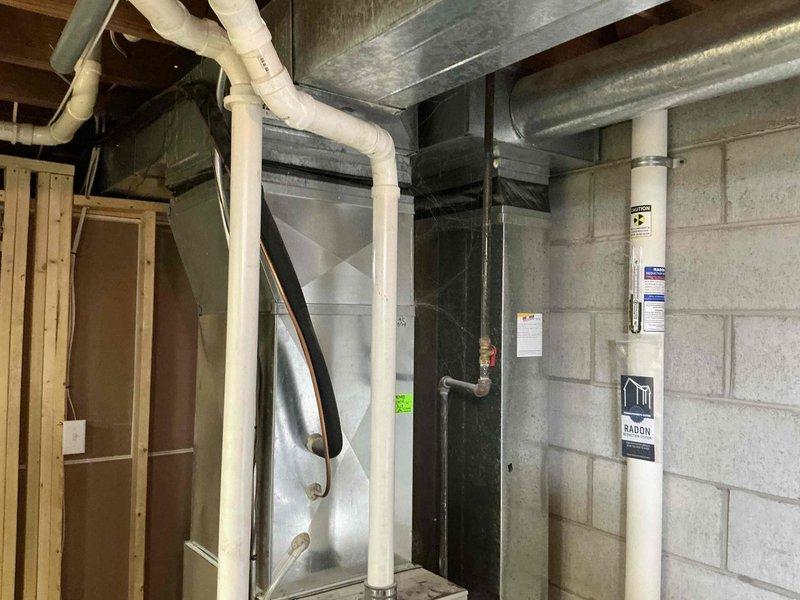 Conducted IAQ assessment on Rheem furnace system in basement utility area. Inspected ventilation components including PVC drainage pipes, metal ductwork, and connections. Documented radon mitigation system integration with HVAC equipment. Photos taken of complete installation for documentation purposes.