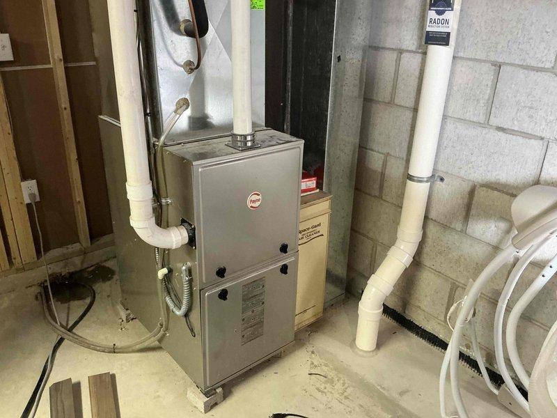 Conducted IAQ assessment on Rheem furnace system in basement utility area. Inspected ventilation components including PVC drainage pipes, metal ductwork, and connections. Documented radon mitigation system integration with HVAC equipment. Photos taken of complete installation for documentation purposes.