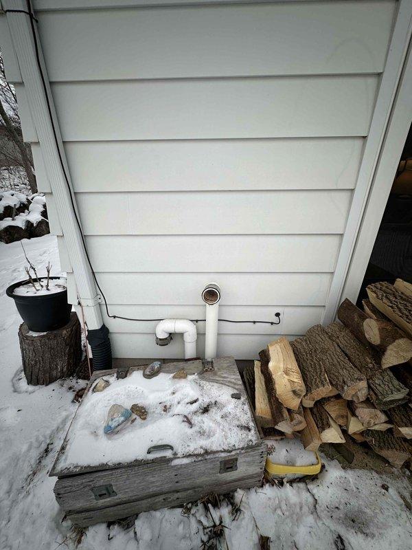 Conducted comprehensive assessment of aging HVAC system in basement utility area showing significant wear. Recommended full system replacement due to deteriorated ductwork with visible seams and compromised metal strapping. Exterior inspection revealed inadequate PVC ventilation configuration that doesn't meet current code requirements.