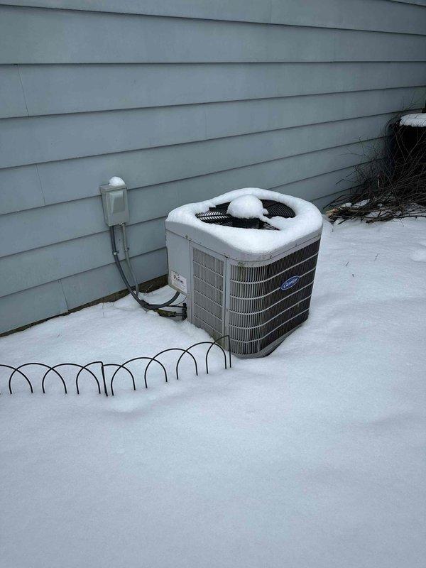Performed site assessment of existing snow-covered Carrier outdoor condenser unit exhibiting signs of age and potential inefficiency. Recommended full system replacement based on observed condition, including accumulated snow on unit which may indicate poor heat transfer and reduced system performance. Documented current installation location adjacent to house with proper electrical disconnect in place for reference during replacement planning.