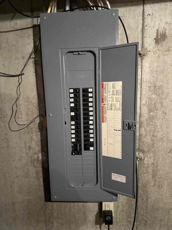 Conducted inspection of existing HVAC system for potential replacement. Examined electrical panel to verify adequate capacity for new equipment. Accessed furnace unit with front panel removed to evaluate internal components and wiring condition. Documented current setup including water heater proximity and PVC ventilation/drainage configuration to determine optimal replacement strategy.