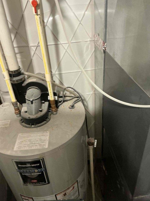 Conducted assessment of existing HVAC system with significant frost accumulation on refrigerant lines and coils of outdoor unit operating in snowy conditions. Recommended replacement of aging Bradford White water heater showing signs of deterioration at connection points, including pressure relief valve. Documented existing installation constraints in utility space to ensure proper sizing and configuration for replacement equipment.