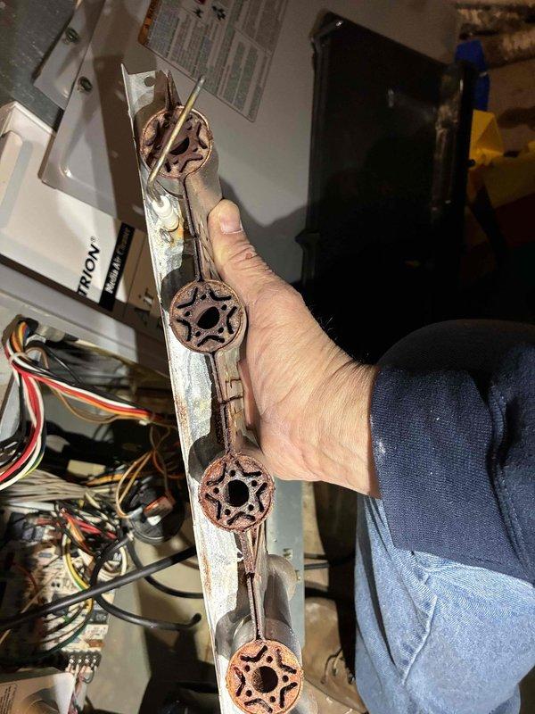 Performed routine tune-up on HVAC system, discovering significant corrosion on mounting bracket and interior components. Removed and replaced deteriorated bracket assembly showing rust damage at connection points, and cleaned accumulated rust stains and water damage from interior housing panel. System now operating within normal parameters after component replacement.