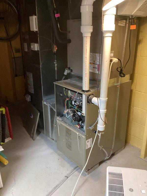 Performed comprehensive IAQ service on residential HVAC system in basement utility area. Inspected furnace internal components including circuit boards and wiring connections, and examined the connected PVC ventilation/drainage system. Serviced wall-mounted humidifier/air purifier unit and checked proper integration with existing metal ductwork and exhaust flue system.