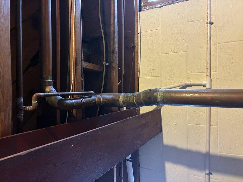 Conducted comprehensive inspection of aging copper piping system in utility area, documenting significant corrosion and deterioration at multiple joint connections. Identified cast iron fitting with visible rust that requires replacement to prevent potential leaks. Recommended full replacement of horizontal copper line section due to extensive discoloration and compromised soldered connections.