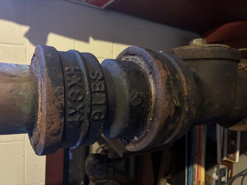 Conducted comprehensive inspection of aging copper piping system in utility area, documenting significant corrosion and deterioration at multiple joint connections. Identified cast iron fitting with visible rust that requires replacement to prevent potential leaks. Recommended full replacement of horizontal copper line section due to extensive discoloration and compromised soldered connections.